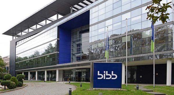 Mehrstöckiges Bürogebäude mit Glasfassade und einem großen blauen Schild, auf dem bibb steht.